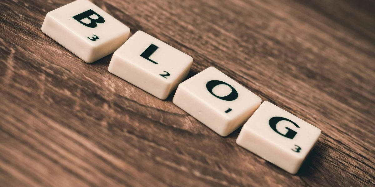 Scrabble tiles spelling 'BLOG' on a wooden background, symbolizing creativity and writing.